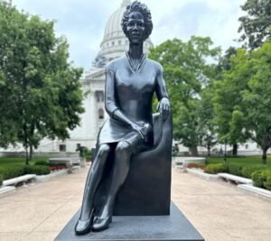 The Vel Phillips statue, unveiled on July 27, 2024, on the Wisconsin State Capitol grounds in Madison, honors a pioneering civil rights leader and public servant. The statue portrays Vel Phillips seated, reflecting her approachable nature and dedication to community engagement. Crafted from clay and cast in silica bronze, it features a semi-matte black patina with a clear protective wax. It rests atop a solid stone plinth milled in Madison.